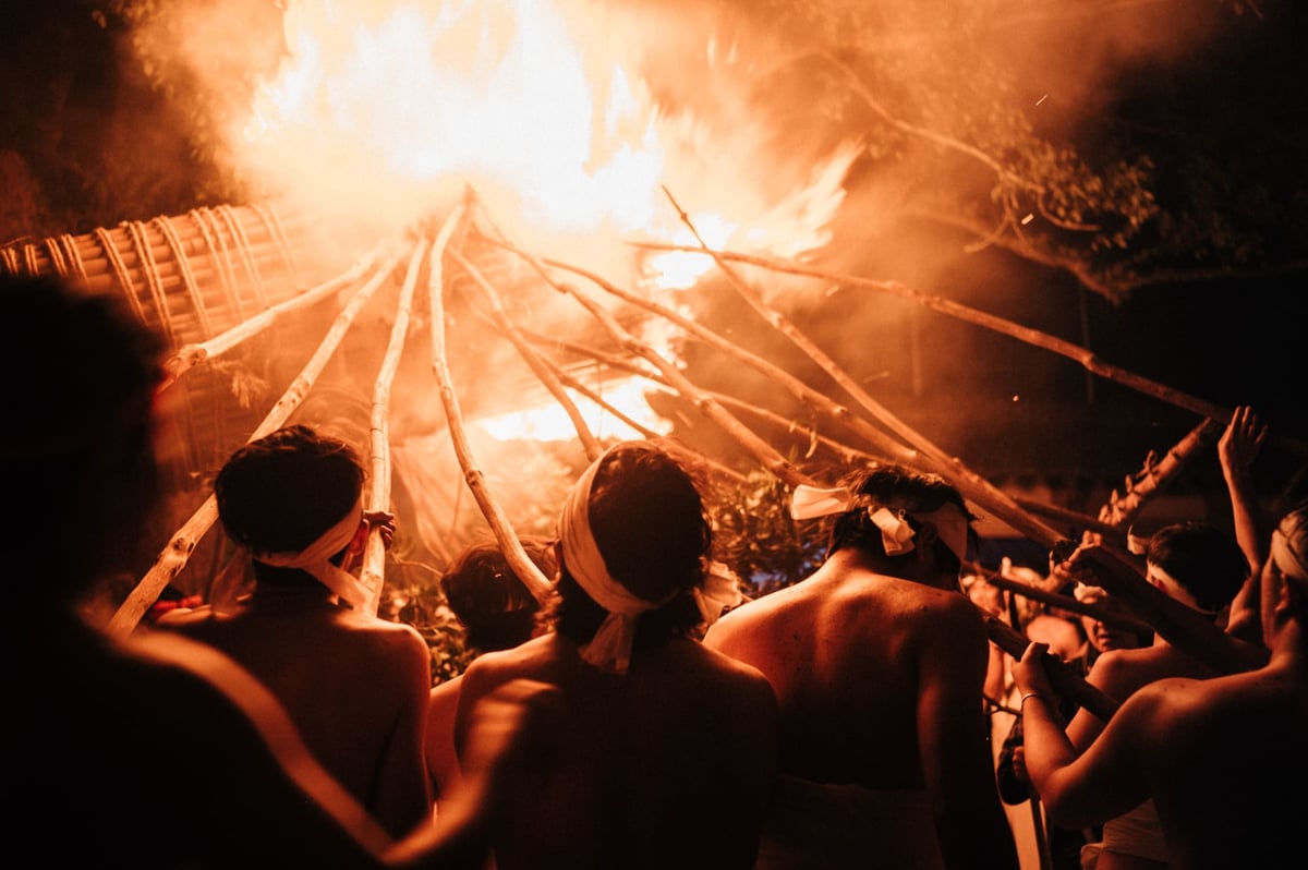 Men move giant torch at the Oniyo fire festival.
