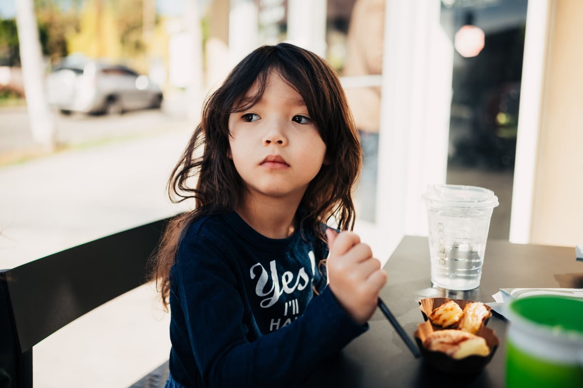 Little Girl Sits at dinner.