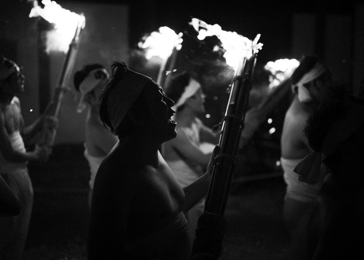 black and white photo of men chanting with torches.