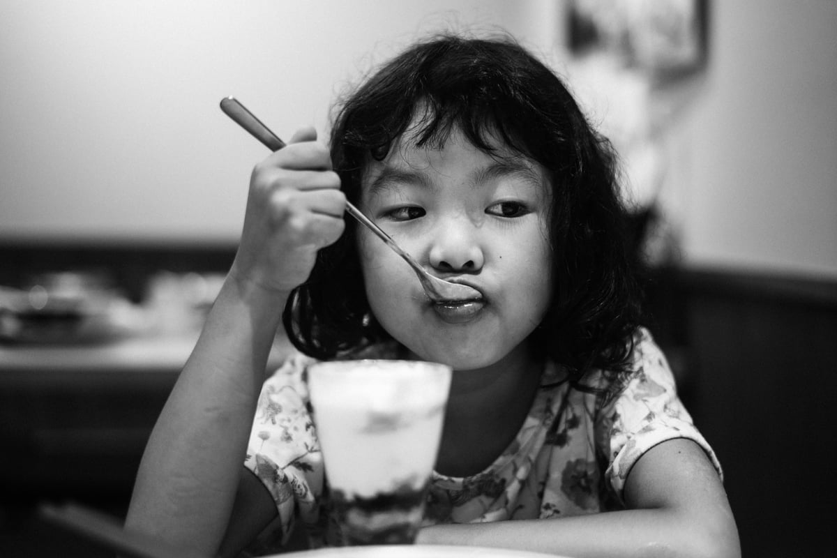 black and white photo of girl eating icecream