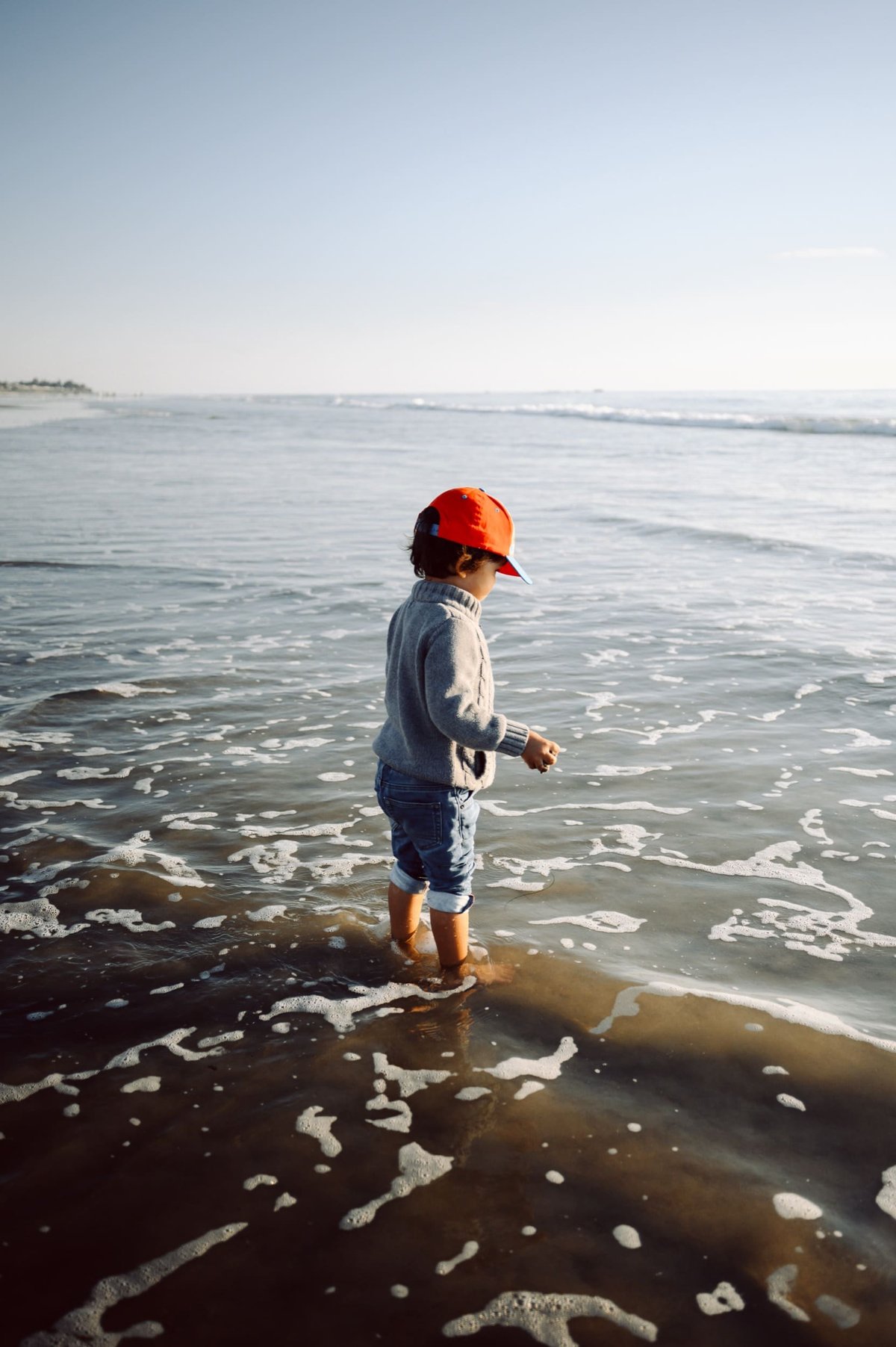 Boy playing on the beach at the San Clemente Pier.