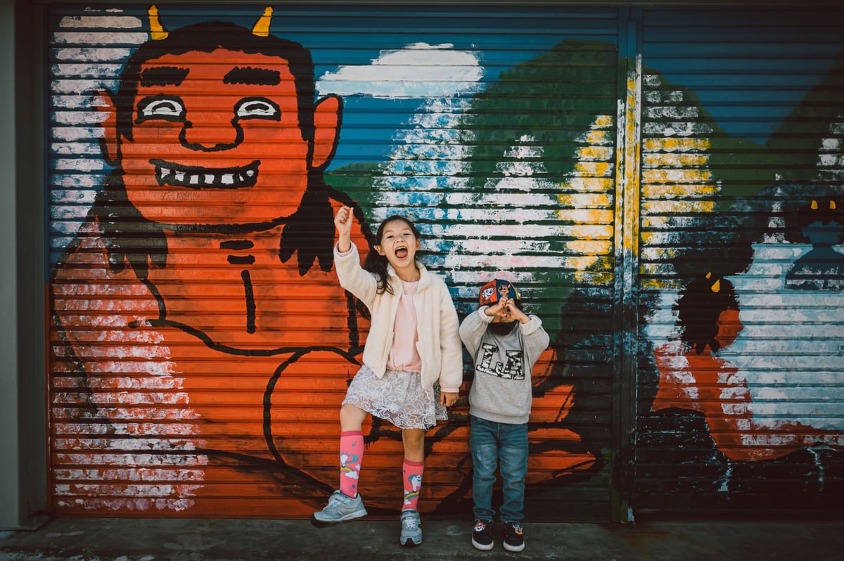 Kids posing in front of painting.