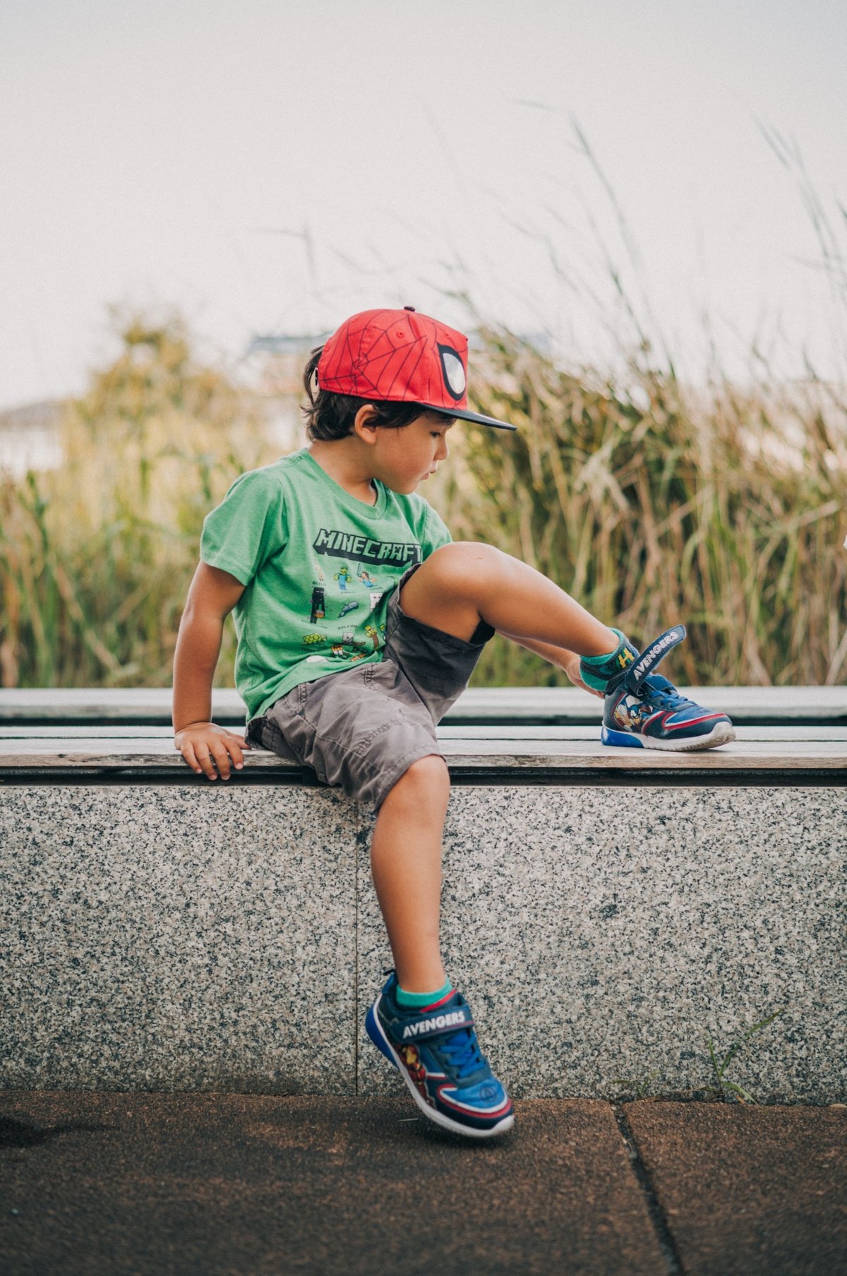 Candid of a little boy at park of boy putting on shoes