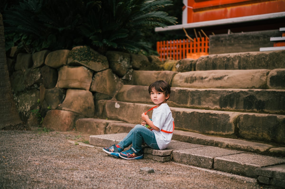 portrait of little boy at the base of stairs of a Japanese temple
